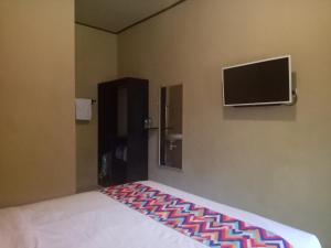 Schlafzimmer mit einem Bett und einem Flachbild-TV in der Unterkunft Ulu Bali Homestay in Jimbaran