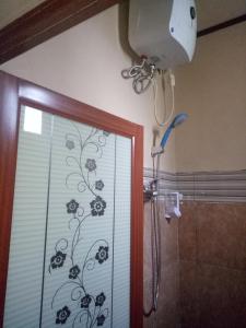 a shower with a glass door with a flower pattern at Ulu Bali Homestay in Jimbaran +7 photos