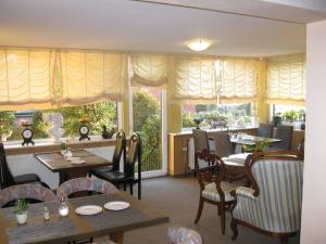 a dining room with tables and chairs and windows at Löns Hotel Garni in Garbsen