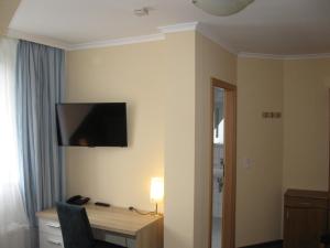 a hotel room with a desk and a television on the wall at Löns Hotel Garni in Garbsen