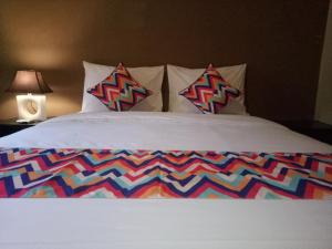 a bed with a colorful comforter and two pillows at Ulu Bali Homestay in Jimbaran