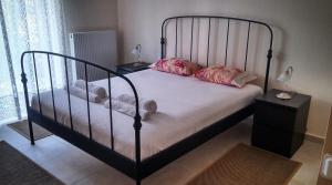 a bedroom with a black bed with pink pillows at Apartment with gardens (ideal for surfers) in Lefkada Town