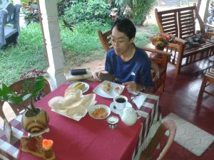 a man sitting at a table with a plate of food at Family Nest in Dambulla