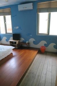 a bedroom with blue walls and a bed and a wooden floor at Being Outdoor in Gongliao
