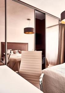 a bedroom with two beds and a chair in front of a mirror at Forest Park by Zoom Apartments in Bratislava