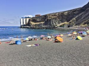 Puerto de la MaderaにあるApartamento Mar y Solの傘持ちの浜辺の人々