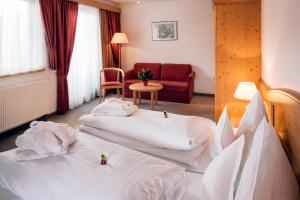 a hotel room with two beds and a couch at Hotel Garni Alpenruh-Micheluzzi in Serfaus