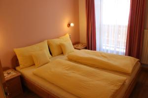 a bedroom with a bed with yellow sheets and a window at Haus Waldruhe in San Candido