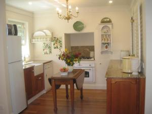 a kitchen with a table and a white refrigerator at Annie's cottage in Kurrajong
