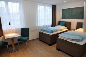 een kamer met 2 bedden en een tafel en stoelen bij Apartments am Freizeitpark in Kriftel