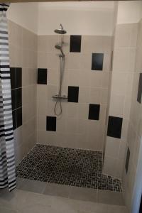 a bathroom with a shower with black and white tile at Ferme Cacheterie, boutique terroir in Fleury-la-Forêt