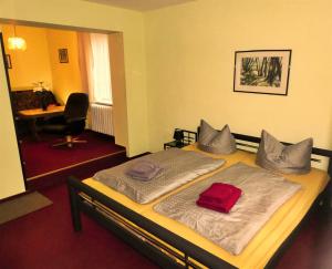 a bedroom with a bed with a red pillow on it at Pension Haus Rodenstein in Altenbrak