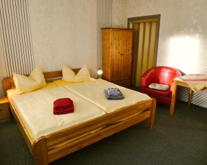 a bedroom with a bed and a red chair at Pension Haus Rodenstein in Altenbrak