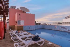Una piscina en la azotea de un edificio con tumbonas. en La Villa Najd Hotel Apartments, en Dubái