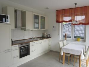 a kitchen with white cabinets and a table with chairs at Ferienwohnung de Jong in Sendenhorst