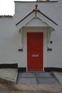 a red door on the side of a building at Little Weech in Dawlish