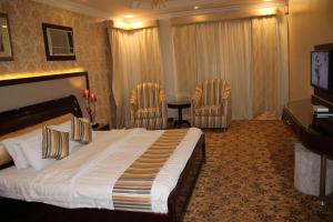 メディナにあるAl Mokhmalia Residential Unitsのベッド1台と椅子2脚が備わるホテルルームです。