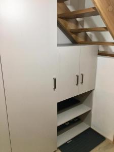 un placard avec des armoires blanches et un escalier en bois dans l'établissement Apartmán 2+kk, à Dolní Morava