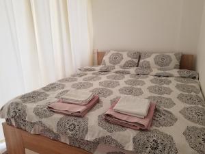 a bed with a black and white comforter with towels on it at Super Central & Panoramic - Leo's Apartment in Pristina