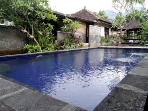 a swimming pool in front of a house at Van Karning Bungalow in Pemuteran