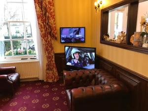 a living room with a leather couch and a television at Balmoral House Hotel in London