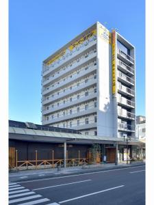 a tall white building with a yellow sign on it at Super Hotel Miyazaki Natural Hot Springs in Miyazaki