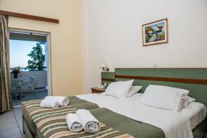 a hotel room with two beds with towels on them at Porto Skala Hotel Village in Skala