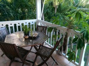 a wooden table and chairs on a porch with plants at Villa Les Nereides in Le Moule