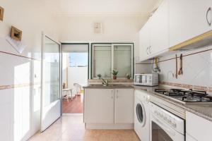a kitchen with white cabinets and a stove top oven at HOME4U - Cosy Apartment with Fantastic Terrace in Cabanas de Tavira