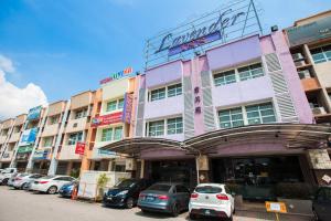 un grand bâtiment avec des voitures garées devant lui dans l'établissement Lavender Inn Permas Jaya, à Johor Bahru