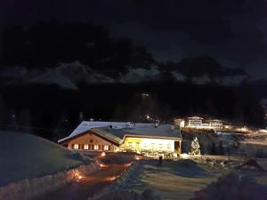 a house with snow on the roof at night at Jägerhaus Agriturismo in Cortina dʼAmpezzo