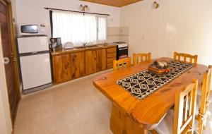 cocina con mesa de madera y nevera blanca en Cabañas Brisas del Jaguel en Santa Teresita