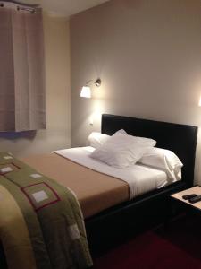 een hotelkamer met een bed met witte kussens bij Hôtel Cuulong in Labarthe-Inard
