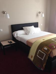 een hotelkamer met een bed en een nachtkastje ernaast bij Hôtel Cuulong in Labarthe-Inard