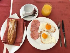 a table with two plates of eggs and sausage and toast at Hôtel Cuulong in Labarthe-Inard