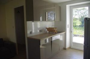 a kitchen with white cabinets and a counter with a window at Gîtes du Clos du Ratz in Arradon