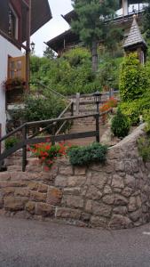 un muro di contenimento in pietra con una recinzione in legno e fiori di Hotel Villa Emilia a Ortisei