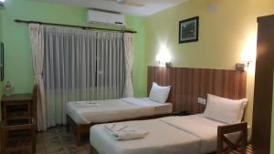 ポカラにあるホテル ビシュラムのベッドが2つと窓があるホテルの部屋