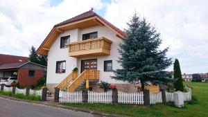 a house with a wooden balcony and a tree at FEWO Brockenblick in Allrode