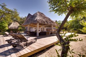 a wooden deck with chairs and a hut at Bayshore Bijou Suites in Maya Beach