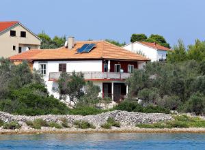 a house on a hill next to the water at Apartmani Nena in Ždrelac