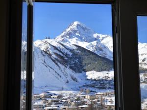 una ventana con vistas a una montaña nevada en Anano Guest House, en Kazbegi