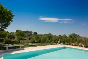 uma piscina com um banco e um céu azul em Trullo la Quiete em Alberobello