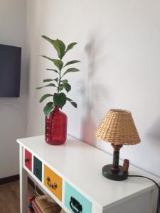 a plant in a red vase on a dresser with a lamp at Casa de Mar @ Porto Côvo in Porto Covo