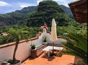balcón con sombrilla y vistas a la montaña en La Casona Azul Boutique Hotel, en Malinalco