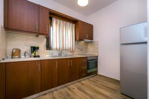 a kitchen with wooden cabinets and a stainless steel refrigerator at Elaionas Stone Houses in Skala Potamias