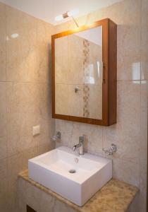 a bathroom with a white sink and a mirror at Elaionas Stone Houses in Skala Potamias