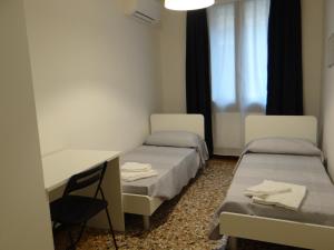 ヴェネツィアにあるPalazzo Boldù - Ca' Colombinaのベッド2台、デスク、窓が備わる客室です。