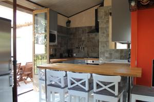 eine Küche mit einer Holztheke und weißen Barhockern in der Unterkunft Entre Ciel et Terre in Besse-sur-Issole