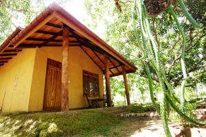 une petite maison jaune au milieu d'une forêt dans l'établissement Bissa Villa, à Habarana